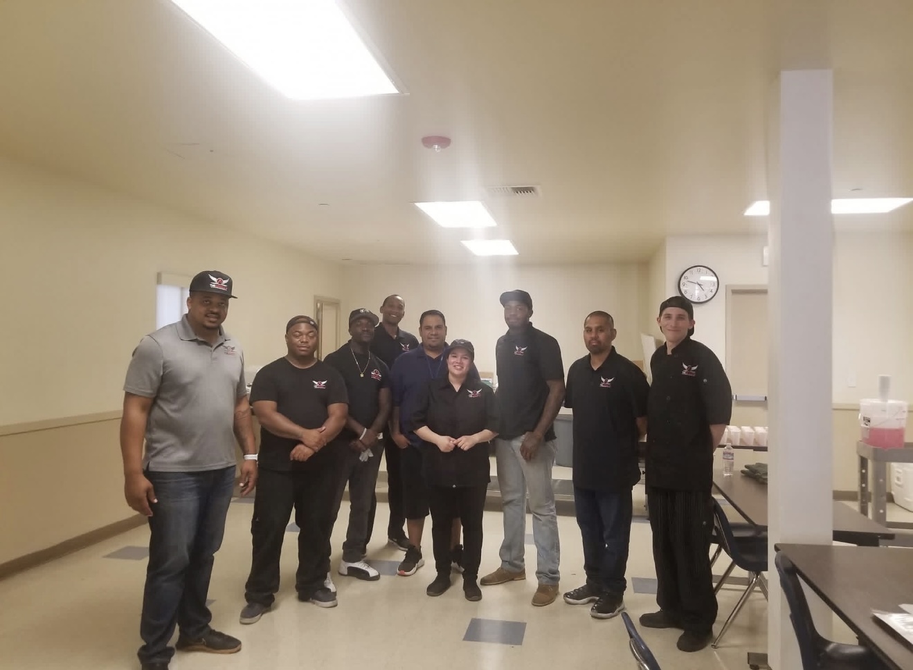 A team of ten, most in black The Admiral's Experience polos, standing together in a dining facility